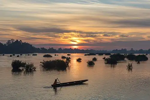 Silhouette d'un pêcheur sur sa pirogue au lever du soleil, à Don Det.