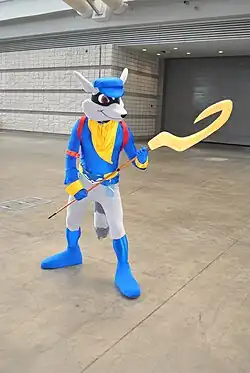 Photo d'un cosplay d'un raton laveur portant une serpe.