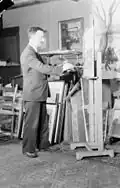 Adrien Hébert peignant un paysage urbain dans son atelier de Montréal, en 1940.