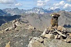 Gros plan sur un cairn sur un sommet entouré de montagnes.