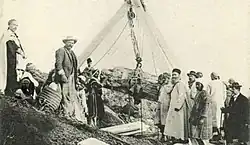 Carte postale ancienne représentant un groupe de personnes autour d'une installation destinée à faire sortir un sarcophage en forme de femme d'un puits funéraire.