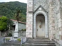Le porche de l'église avec une statue de Notre-Dame de Lourdes, à gauche le monument aux morts