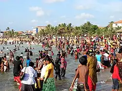 Une plage pleine de monde, dont beaucoup vont à l’eau avec leur vêtements