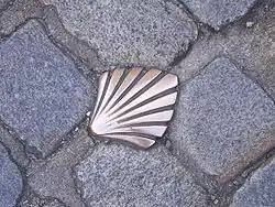 photographie d'une coquille Saint-Jacques en cuivre insérée dans les pavés d'une rue de Limoges et marquant le passage de la Via Lemovicensis menant à Saint-Jacques de Compostelle