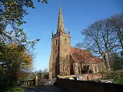 Photo d'un bâtiment avec une grande tour carrée au toit crénelé et coiffé d'une haute flèche