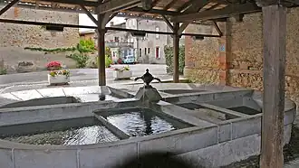 Sur le sentier de l'eau, le lavoir couvert. A raison de 3 ou 4 membres par famille, il pouvait accueillir une douzaine de lavandières qui tapaient le linge avec le « basel » (le battoir).