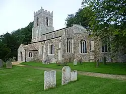 Photo d'un bâtiment allongé flanqué d'une grande tour carrée et entouré d'arbres