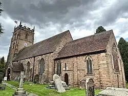 Photo en contre-plongée d'un bâtiment allongé flanqué d'une tour carrée à créneaux sur laquelle flotte le drapeau du Royaume-Uni