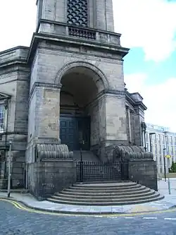 Bâtiment de pierre. Haut porche précédé d'un vaste perron