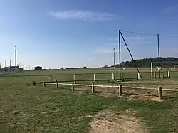 Photographie en couleurs d'un terrain engazonné avec plusieurs équipements sportifs.