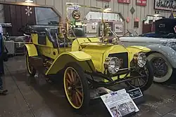 Photo d'une voiture ancienne jaune, prise légèrement du côté avant gauche.