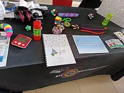 Table présentant un casque anti-bruit, des stim toys et autres objets de couleurs aidant les personnes autistes.