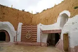 Photo d'une maison taillée dans la roche avec des soubassements blancs.