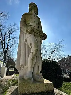 statue en pierre, en calcaire ou en marbre, texture poreuse, traces de mousse ou d'altération visibles sur sa surface, sculptures extérieures, homme sculpté.