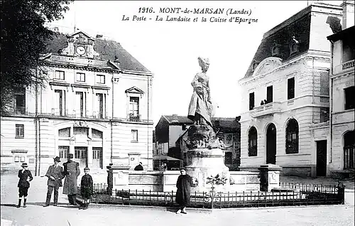 Photo ancienne de la place Pascal-Duprat (actuelle place du Général-Leclerc), ornée de la statue La Landaise avec le bâtiment de la Poste (au n°7, à gauche) et de la Caisse d'Epargne (au n°6, à droite).