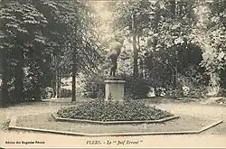 Photographie en noir et blanc représentant une statue en bronze au milieu d'un square avec des arbres en arrière-plan.