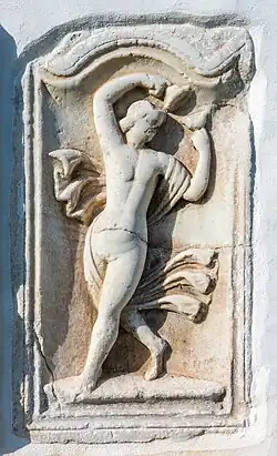 Femme nue dansant , jouant de crotales, bras levés. Un voile s'enroulant autour d’elle accentue le mouvement.