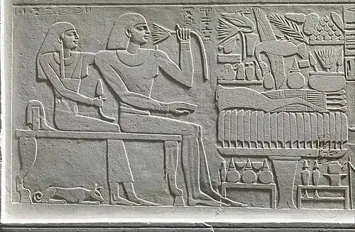 Antef, surveillant de la forteresse, et son épouse attablés devant leur table d'offrandes, XIe dynastie (Metropolitan Museum of Art).