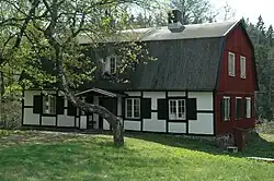 Bâtiment ancien avec une façade rouge et une façade noire et blanche, avec un arbre au premier plan.