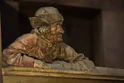 Photographie de la statue d'un homme, accoudé à une balustrade.