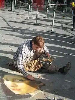 Un artiste de rue (un madonnaro) à l’œuvre piazza Beaubourg (2005), reproduisant au sol La Jeune Fille à la perle de Vermeer de Delft.