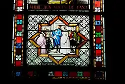 Photographie en couleur d'un vitrail figurant un homme tenant le bras d'une femme.