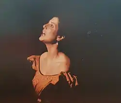 Photographie en couleurs traitée en clair obscur d'une femme brune chantant.