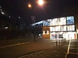 Photographie de nuit de la gare de départ avec des fenêtres éclairées et des lampadaires.