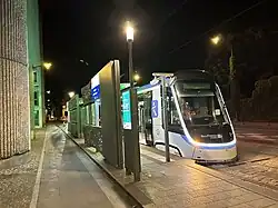 Face avant de la rame TW 20 no 4 à la station Cimetière de Saint-Denis en essais nocturnes dans une livrée blanche avec le logo IDFM en bleu sur le flanc. Le nez de la rame est parcouru par un bandeau lumineux blanc