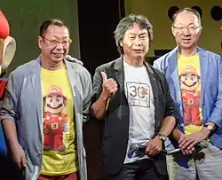 Trois hommes d'une cinquantaine d'années, micros en main, portant des t-shirts rendant hommage au personnage de Mario.