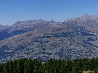 La Pierra Menta encadrée par la Grande Paréi à gauche et le Roignais à droite avec devant eux le dôme de Vaugelaz depuis Peisey-Vallandry de l'autre côté de la vallée de la Tarentaise au sud-est.
