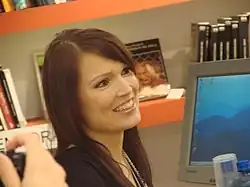 Image d'une femme brune souriante habillée de noir