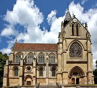 Notre-Dame de l'Assomption à Taverny, vue latérale avec à droite, le porche principal (porte du roi Jean), séparé du clocher par une rosace en vitrail ; à gauche, série de quatre vitraux en ogive, avec remplages de pierre très travaillés. Au-dessous, bas-côtés avec série de trois vitraux en ogive. Sous le second emplacement à partir de la gauche, porte secondaire d'entrée, surmontée d'un petit vitrail en œil-de-bœuf. On distingue très nettement les contreforts.