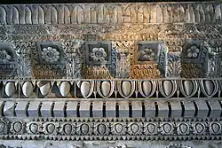 Détail de la partie supérieure de l'entablement du temple. On voit entre chaque denticule un motif composé de deux anneaux accolés, signature possible de l'architecte Rabirius.