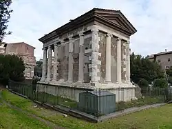 Photographie en couleurs d'un édifice antique dont les murs sont rythmés par des colonnes.