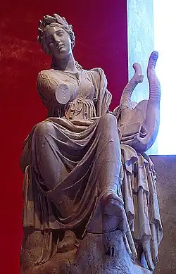 Statue d'une femme assise vue de face, un drapé sur les jambes et une lyre sur sa gauche.