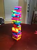 Partie du jeu de société Jenga, avec des blocs colorés rappelant les tétriminos.