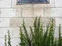 Photographie en couleurs d'un bloc de pierre gravé inclus dans une maçonnerie plus récéente.