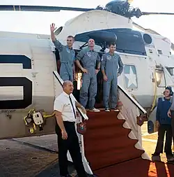 Photographie couleur des trois hommes d'Apollo 10 sortant d'un hélicoptère posé sur un porte-avions.