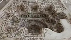 Vue du baptistère avec un côté endommagé et des fragments d'inscriptions