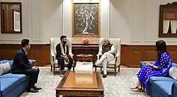 Photographie d'une rencontre officielle entre quatre personnes assises sur des fauteils.