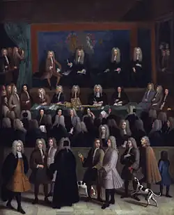 Un grand nombre de personnes en perruques et robes noires sont réunies dans une vaste pièce. Une grande fresque royale orne le mur du fond, devant lequel sont assis quatre juges. Devant eux, une trentaine de greffiers sont assis autour d'une table, sur laquelle reposent un sceptre et un coussin.