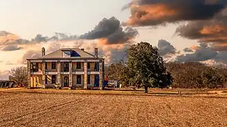 Photo d'une maison avec un champ et des arbres.