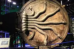 Une porte circulaire incrustée de sept serpents de pierre