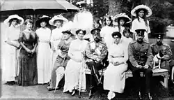 Photographie en noir et blanc montrant un groupe composé de sept femmes, quatre hommes et cinq fillettes et adolescentes.