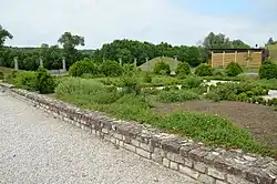 Vue d'un jardin avec à l'arrière-plan une colonnade et des tumulus.