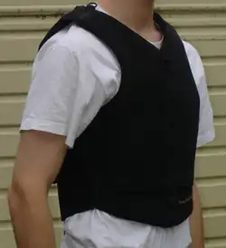 Un gilet de protection noir porté par un homme blanc dont on ne voit pas la tête