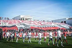 Photographie du Pesage Est au Stade des Costières et du tifo des Gladiators Nîmes 1991, groupe de supporters du Nîmes Olympique.