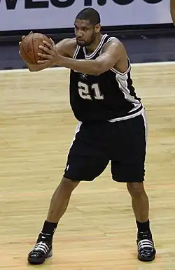A man of lighter complexion holds a basketball while playing in a basketball game.