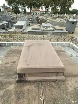 Photographie d’une pierre tombale dans un cimetière.